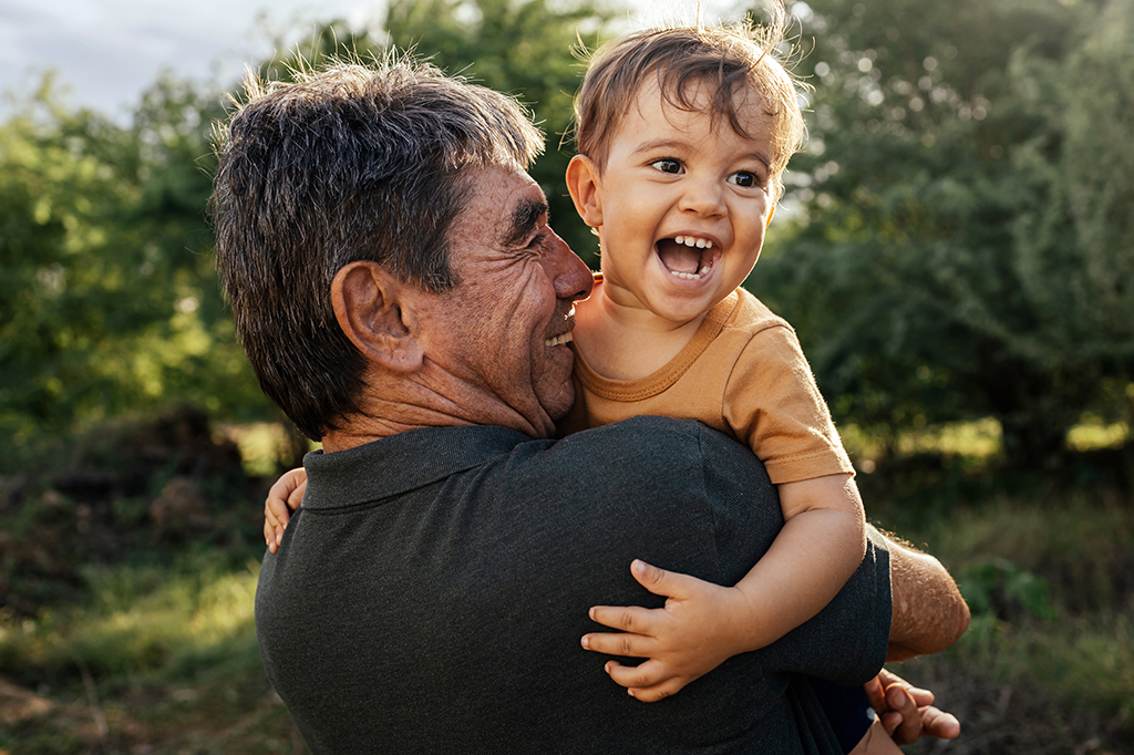 Grandfather spending time with his grandson in park on sunny day