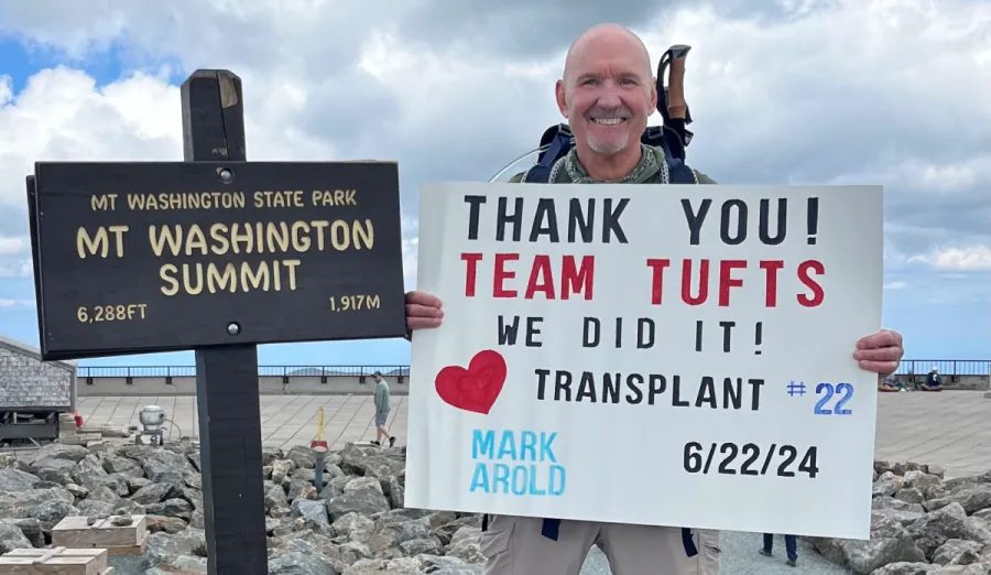 Mark Arold holding a sign at the top of Mt. Washington