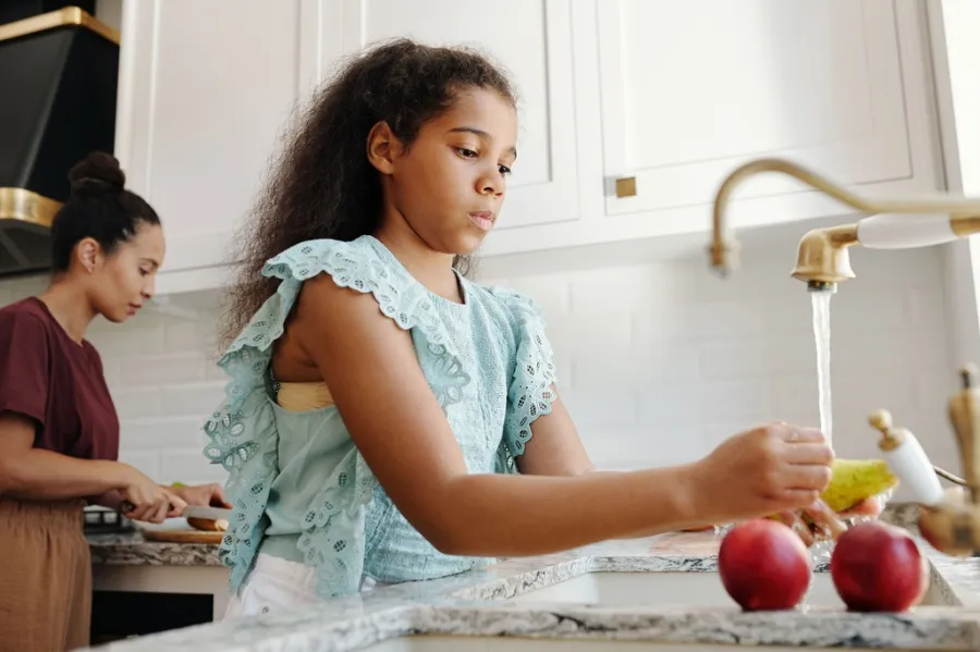 Young person washing fruit in the kitchen sink to avoid cyclospora