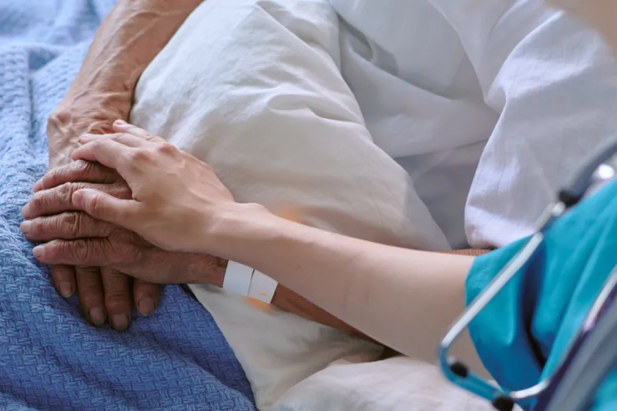 A clinician showing comfort to a patient in a hospital bed