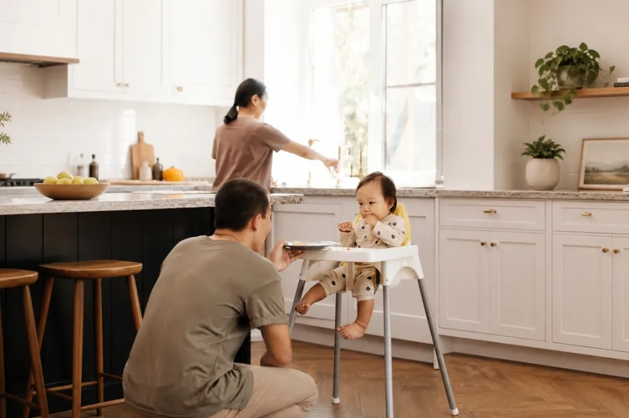 Man feeding baby in highchair