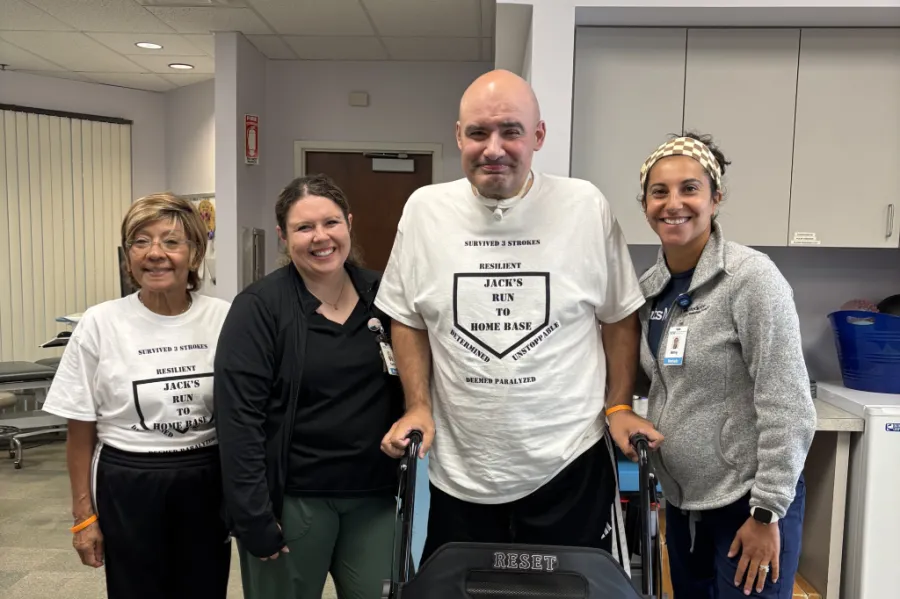 Man on a walker smiling with a group of women.