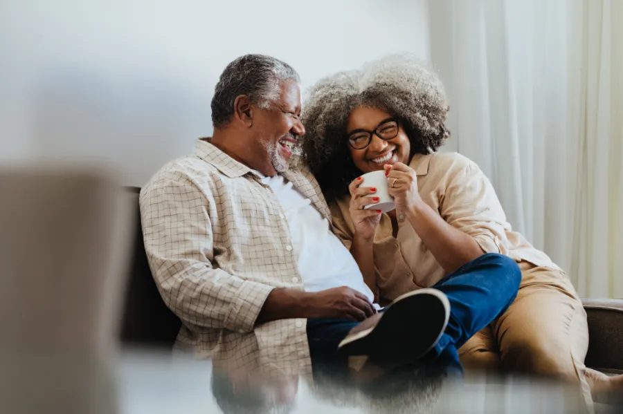 An older couple on a couch, sharing a laugh