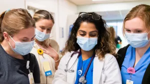 Physician Assistant, Rakhi Patel reviewing clinical information on a computer with nurses (Elizabeth Levesque, Delaney McCarthy and Fionna Donovan) in the neurology trauma unit at Tufts Medical Center. 