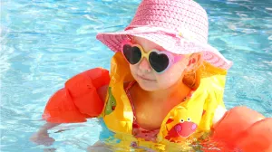 Toddler in pool with floaties and sunglasses