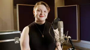 Person stands in a music studio in front of a microphone