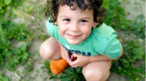 Toddler with dark curly hair looking up at camera and smiling