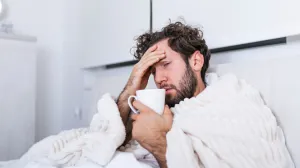 Man who is sick with the flu in bed with tea