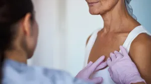 Breast cancer nurse navigator performing a gentle chest exam on a patient, offering supportive, personalized care.