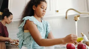 Young person washing fruit in the kitchen sink to avoid cyclospora
