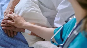 A clinician showing comfort to a patient in a hospital bed