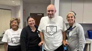 Man on a walker smiling with a group of women.