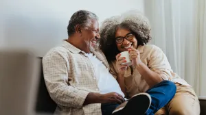 An older couple on a couch, sharing a laugh
