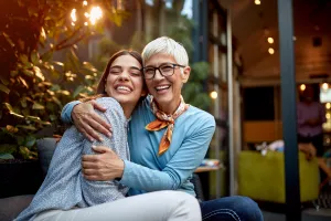 Mother and daughter hugging in backyard. 