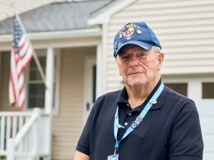 Portrait of Care at Home volunteer, Thomas Murphey, in front of a home with an American flag.
