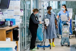 Nurses Rachel DiRaimo and Bridget Endicott walking laps with critical care unit patient at Tufts Medical Center.