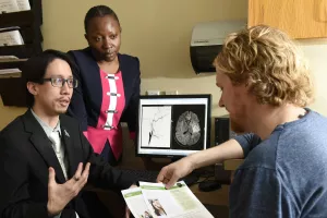 Lester Leung, MD, Director, Comprehensive Stroke Center at Tufts Medical Center; Director, Stroke and Young Adults (SAYA) Program, and Adedayu Dansu, Stroke Coordinator, adult neurology, discussing brain scans, condition with patient. 
