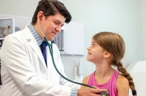 James Goodman, MD of Circle Health and Pelham Family Practice listening to a pediatric patient's heart with a stethoscope during a primary care appointment.