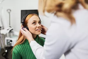 Doctor adjusting headphones on patient during a hearing test at an appointment in the clinic.