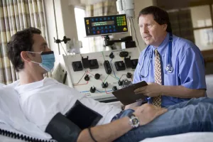 Ray Comenzo, MD (Director of Blood Bank, Transfusion and Stem Cell Services at Tufts Medical Center) examining patient during an appointment with aphoresis equipment.