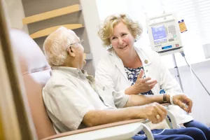 Barbara Gregoire, RN talks to patient during treatment in the Infusion Center at Tufts Medical Center's Cancer Center.