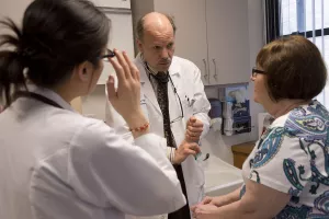 Nicholas Hill, MD (Chief, Pulmonary, Sleep and Critical Care at Tufts Medical Center) examines and talks to patient while fellow Lily Wong looks on.