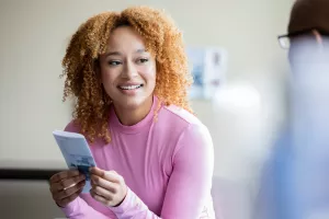 Patient smiling and holding a brochure during a clinic appointment while listening to doctor. =
