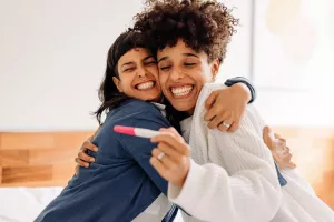 An LGBTQ couple celebrating with a positive at-home pregnancy test.
