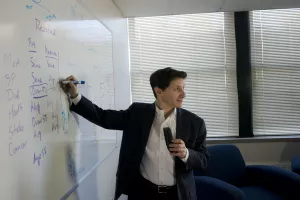 Peter Neumann, ScD, Director, Center for the Evaluation of Value and Risk in Health at the Institute for Clinical Research and Health Policy Studies works with colleague at whiteboard.