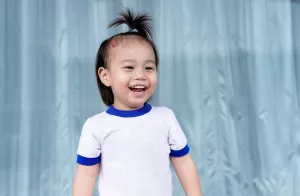 Child with birthmark on forehead is laughing.