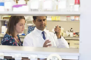 Jatin Roper, MD, Director of the Center for Hereditary Gastrointestinal Cancer at Tufts Medical Center and Chelsea Mandigo, Genetic Counselor in laboratory using a pipet for a genetics test.