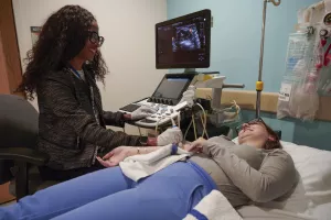 A CRA radiologist at Tufts Medical Center is performing an ultrasound scan on a patient's arm.