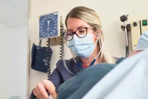 Nurse Practitioner, Natalie Bonvie-Hill, listening to patient's heart with a stethoscope during a cardiovascular appointment at Tufts Medical Center.
