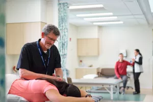Todd Haynes, Physical Therapist at MelroseWakefield Hospital's 888 Main rehabilitation office, massages shoulder of patient on table. 