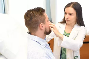 Natalia Plotnikova, MD, examines a patient's skin around the nose in the dermatology clinic at Tufts Medical Center.