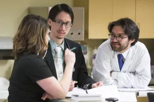 Lester Leung, MD (Director, Comprehensive Stroke Center; Director, Stroke and Young Adults (SAYA) Program), Cara Clifford, MA CCC-SLP (speech language pathologist) and Ali Daneshmand, MD (Neurology senior resident) discussing a case in the Neuro Trauma Unit at Tufts Medical Center.