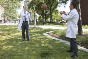 Orthopedic Surgeon and Chief of Sports Medicine at Tufts Medical Center, Matthew Salzler, MD throwing a basketball outside with another doctor.