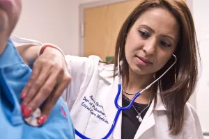 Pulmonologist Aarti Grover, MD (Medical Director, Center for Sleep Medicine) examines patient using a stethoscope during a pulmonology appointment at Tufts Medical Center.