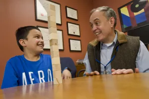  Center for Children with Special Needs (CCSN) clinician Eric von Hahn, MD stacking wooden blocks with patient during an appointment at Tufts Medical Center.