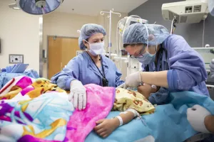 Doctor and nurse at Tufts Medical Center working together in operating room during a pediatric surgery.