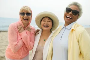 Three women laughing together on a beach