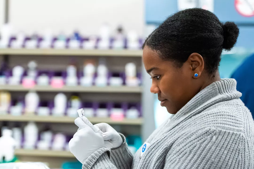 Nicole Irish, RPh, a Clinical Pharmacist at Tufts Medical Center, is checking and preparing the dosage of a medication in the pharmacy department.