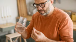 Man taking pill with glass of water