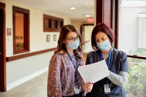 Director of Clinical Services meeting with Hospice Clinician/Social Worker in the hallway of High Point House at Care at Home.