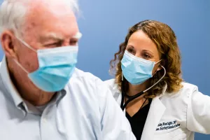 Cynthia Enright, NP using a stethoscope to check a patient's heart during an EP (Electrophysiology) lab appointment at Tufts Medical Center.